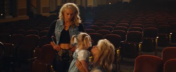 Movie still from “The Dirt” (2019), directed by Jeff Tremaine – Two women and a child in a theater; Medium shot, Over the shoulder angle