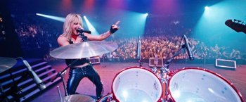 Movie still from “The Dirt” (2019), directed by Jeff Tremaine – A person on a stage with a drum set; Wide shot, Overhead angle