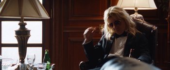 Movie still from “The Dirt” (2019), directed by Jeff Tremaine – A woman sitting on a chair in front of a wooden wall; Medium shot, Over the shoulder angle