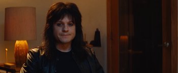 Movie still from “The Dirt” (2019), directed by Jeff Tremaine – A person with long black hair wearing a leather jacket; Close Up shot, Over the shoulder angle