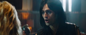 Movie still from “The Dirt” (2019), directed by Jeff Tremaine – A man with long hair and a black shirt is looking to his left; Close Up shot, Over the shoulder angle