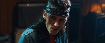 Movie still from “The Dirt” (2019), directed by Jeff Tremaine – A man with long black hair and a bandana on his head; Close Up shot, Low angle