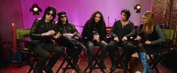 Movie still from “The Dirt” (2019), directed by Jeff Tremaine – A group of men sitting in a row on folding stools; Medium shot, High angle