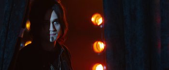 Movie still from “The Dirt” (2019), directed by Jeff Tremaine – A man standing in front of some lights at night; Medium shot, Over the shoulder angle