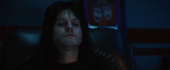 Movie still from “The Dirt” (2019), directed by Jeff Tremaine – A person with long black hair is sitting in a chair; Close Up shot, Low angle