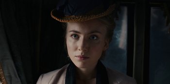 Movie still from “The Empress” (2022), created by Katharina Eyssen – A woman wearing a hat and a jacket looking at the camera; Close Up shot, Low angle