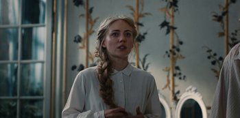 Movie still from “The Empress” (2022), created by Katharina Eyssen – A young woman with a braid in front of a wall; Close Up shot, Over the shoulder angle