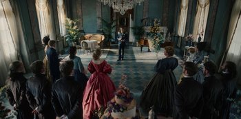 Movie still from “The Empress” (2022), created by Katharina Eyssen – A group of people sitting in a room with cakes; Wide shot, High angle