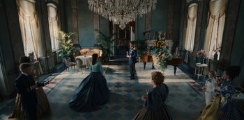 Movie still from “The Empress” (2022), created by Katharina Eyssen – A group of people standing around in a room; Wide shot, High angle