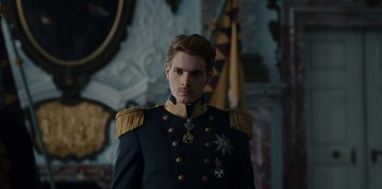 Movie still from “The Empress” (2022), created by Katharina Eyssen – A man in a military uniform standing in front of a flag; Close Up shot, Low angle