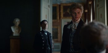 Movie still from “The Empress” (2022), created by Katharina Eyssen – A man in a suit standing next to another man in a suit; Medium shot, Over the shoulder angle