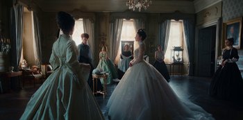 Movie still from “The Empress” (2022), created by Katharina Eyssen – A group of people sitting in a living room; Wide shot, Over the shoulder angle