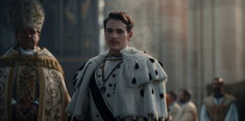 Movie still from “The Empress” (2022), created by Katharina Eyssen – A man in a white fur coat and a black and white tie; Medium shot, Low angle