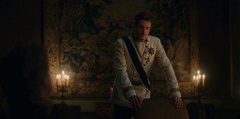 Movie still from “The Empress” (2022), created by Katharina Eyssen – A man in a white suit standing in front of a painting; Medium shot, Over the shoulder angle