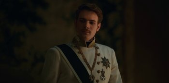 Movie still from “The Empress” (2022), created by Katharina Eyssen – A man in a white suit with medals around his neck; Close Up shot, Low angle