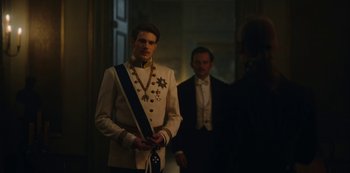 Movie still from “The Empress” (2022), created by Katharina Eyssen – A man in a white suit standing next to another man in a black suit; Medium shot, Over the shoulder angle