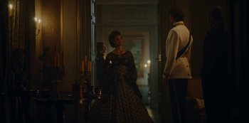 Movie still from “The Empress” (2022), created by Katharina Eyssen – A man and a woman dressed in period clothing in front of a doorway; Medium shot, Over the shoulder angle