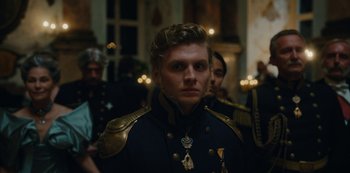 Movie still from “The Empress” (2022), created by Katharina Eyssen – A man in a military uniform standing in front of a group of people; Close Up shot, Over the shoulder angle