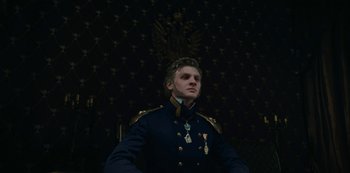 Movie still from “The Empress” (2022), created by Katharina Eyssen – A man in a military uniform standing in front of a wall; Medium shot, Low angle