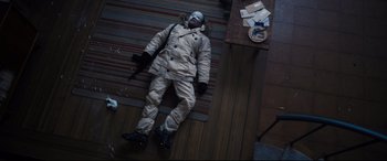 Movie still from “No Time to Die” (2021), directed by Cary Joji Fukunaga – A man in a snow suit is laying on the floor; Wide shot, Overhead angle