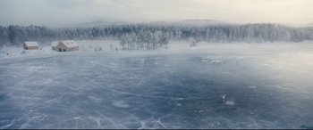 Movie still from “No Time to Die” (2021), directed by Cary Joji Fukunaga – A view of a frozen lake with trees in the background; Extreme Wide shot, High angle