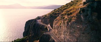 Movie still from “No Time to Die” (2021), directed by Cary Joji Fukunaga – An aerial view of a road on the side of a mountain; Extreme Wide shot, High angle