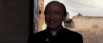 Movie still from “No Time to Die” (2021), directed by Cary Joji Fukunaga – A man in a uniform smiling for the camera; Close Up shot, Over the shoulder angle