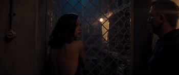 Movie still from “No Time to Die” (2021), directed by Cary Joji Fukunaga – A woman standing next to a metal fence at night; Medium shot, Low angle