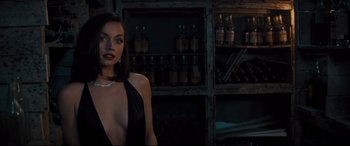 Movie still from “No Time to Die” (2021), directed by Cary Joji Fukunaga – A woman in a black dress standing in front of a bar; Medium shot, Over the shoulder angle