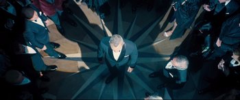Movie still from “No Time to Die” (2021), directed by Cary Joji Fukunaga – An overhead view of a man in a suit and tie; Wide shot, Overhead angle