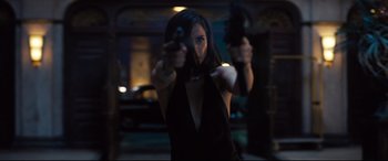 Movie still from “No Time to Die” (2021), directed by Cary Joji Fukunaga – A woman holding a gun in her hands; Medium shot, Low angle