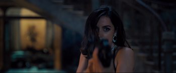 Movie still from “No Time to Die” (2021), directed by Cary Joji Fukunaga – A beautiful woman holding a gun in a dark room; Close Up shot, Over the shoulder angle