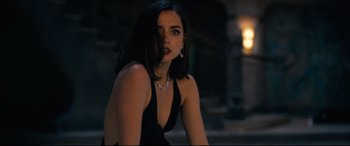 Movie still from “No Time to Die” (2021), directed by Cary Joji Fukunaga – A woman in a black dress sitting in the dark; Close Up shot, Over the shoulder angle