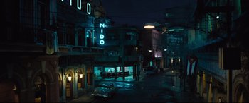 Movie still from “No Time to Die” (2021), directed by Cary Joji Fukunaga – A street scene at night with cars parked on the side of the road; Extreme Wide shot, High angle