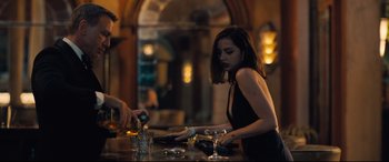 Movie still from “No Time to Die” (2021), directed by Cary Joji Fukunaga – A woman in a black dress at a bar; Medium shot, Over the shoulder angle