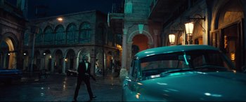 Movie still from “No Time to Die” (2021), directed by Cary Joji Fukunaga – A man in a tuxedo walking past a classic car; Wide shot, Low angle