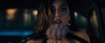 Movie still from “No Time to Die” (2021), directed by Cary Joji Fukunaga – A beautiful young lady sitting in a car holding a steering wheel; Close Up shot, Over the shoulder angle