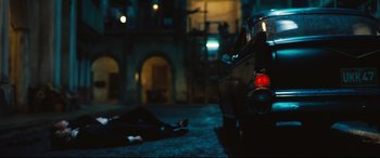 Movie still from “No Time to Die” (2021), directed by Cary Joji Fukunaga – A person laying on the ground next to a motorcycle; Wide shot, Overhead angle