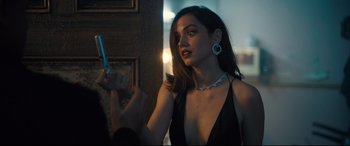 Movie still from “No Time to Die” (2021), directed by Cary Joji Fukunaga – A woman in a black dress holding a cell phone; Close Up shot, Over the shoulder angle