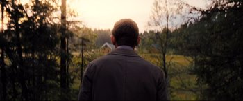 Movie still from “No Time to Die” (2021), directed by Cary Joji Fukunaga – A man standing in front of trees looking out a window; Medium shot, Over the shoulder angle