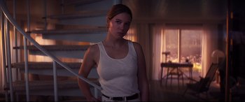 Movie still from “No Time to Die” (2021), directed by Cary Joji Fukunaga – A woman holding a sword in a room with stairs in the background; Medium shot, Low angle