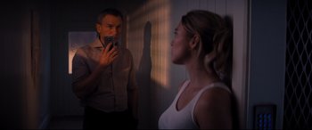 Movie still from “No Time to Die” (2021), directed by Cary Joji Fukunaga – A man taking a picture of a woman in the mirror; Medium shot, Low angle