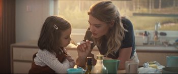 Movie still from “No Time to Die” (2021), directed by Cary Joji Fukunaga – A woman and a child are eating at a table; Medium shot, Over the shoulder angle