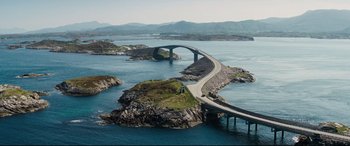 Movie still from “No Time to Die” (2021), directed by Cary Joji Fukunaga – An aerial view of a bridge over a body of water; Extreme Wide shot, High angle