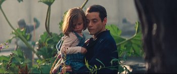 Movie still from “No Time to Die” (2021), directed by Cary Joji Fukunaga – A man holding a little girl in his arms; Close Up shot, Low angle