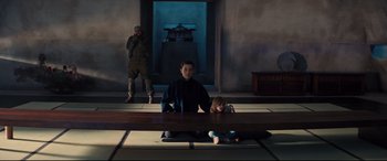 Movie still from “No Time to Die” (2021), directed by Cary Joji Fukunaga – A man sitting on the ground next to a child; Wide shot, Low angle