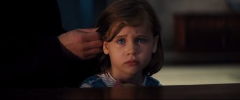 Movie still from “No Time to Die” (2021), directed by Cary Joji Fukunaga – A little girl with blue eyes is looking at the camera; Close Up shot, Over the shoulder angle