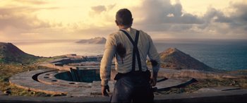 Movie still from “No Time to Die” (2021), directed by Cary Joji Fukunaga – A man standing on top of a hill looking out at the ocean; Wide shot, High angle