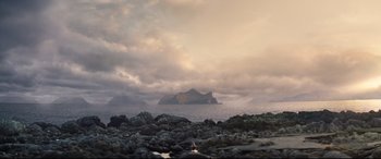 Movie still from “No Time to Die” (2021), directed by Cary Joji Fukunaga – A person standing on the rocks looking out at the ocean; Extreme Wide shot, Low angle