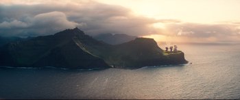 Movie still from “No Time to Die” (2021), directed by Cary Joji Fukunaga – The sun is setting over a large body of water; Extreme Wide shot, High angle